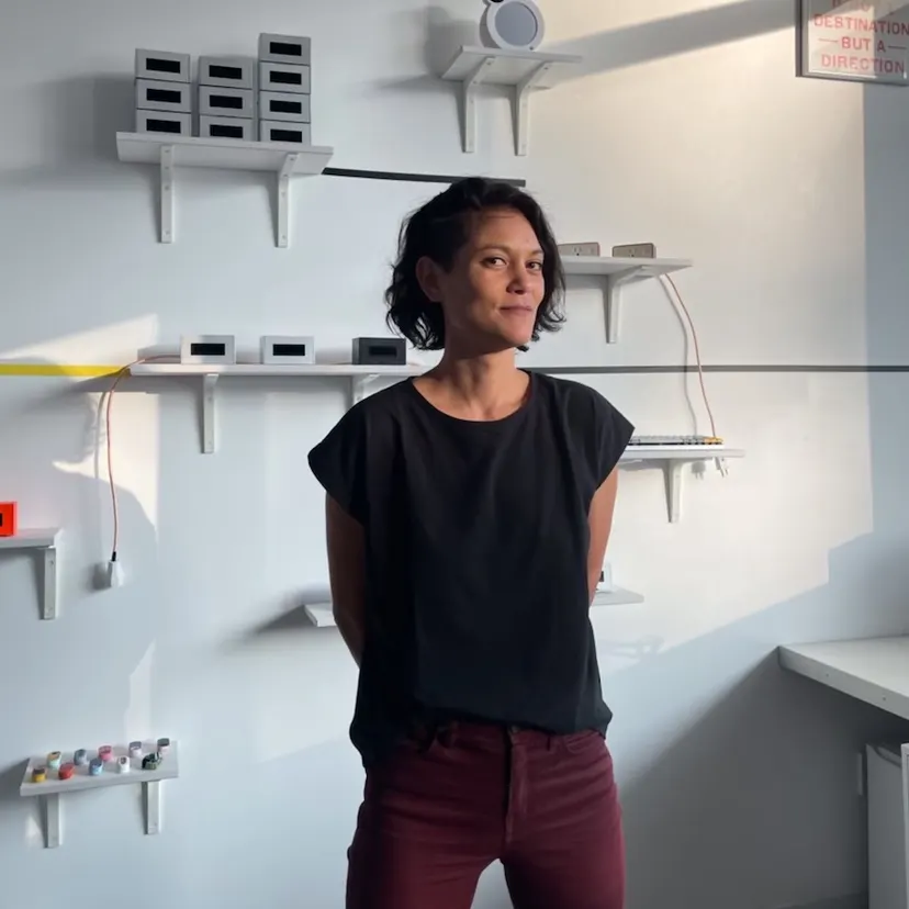 A Chinese-American woman with short dark hair standing in front of device sculptures.