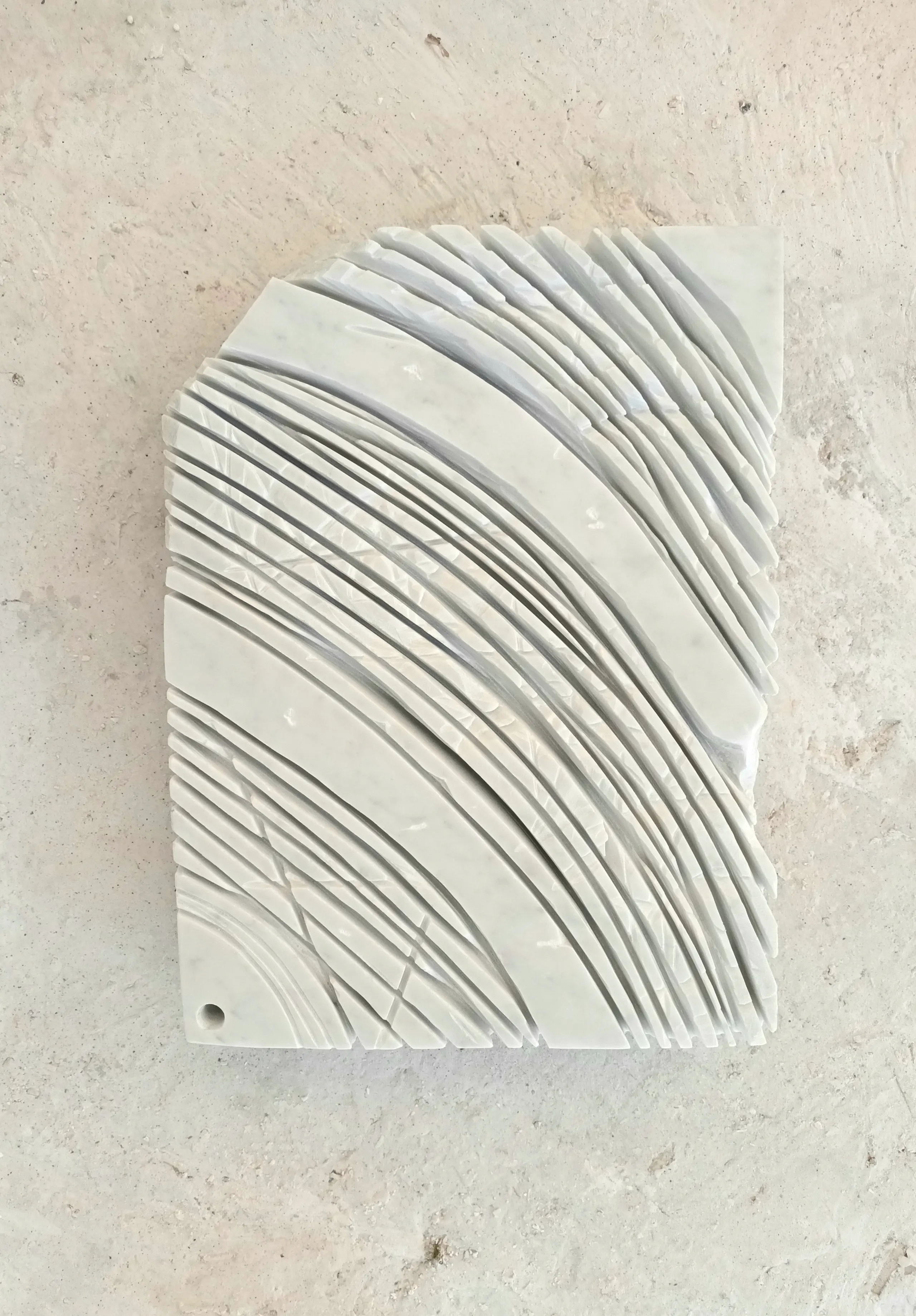 Photo of flat white stone with curved lines carved into it