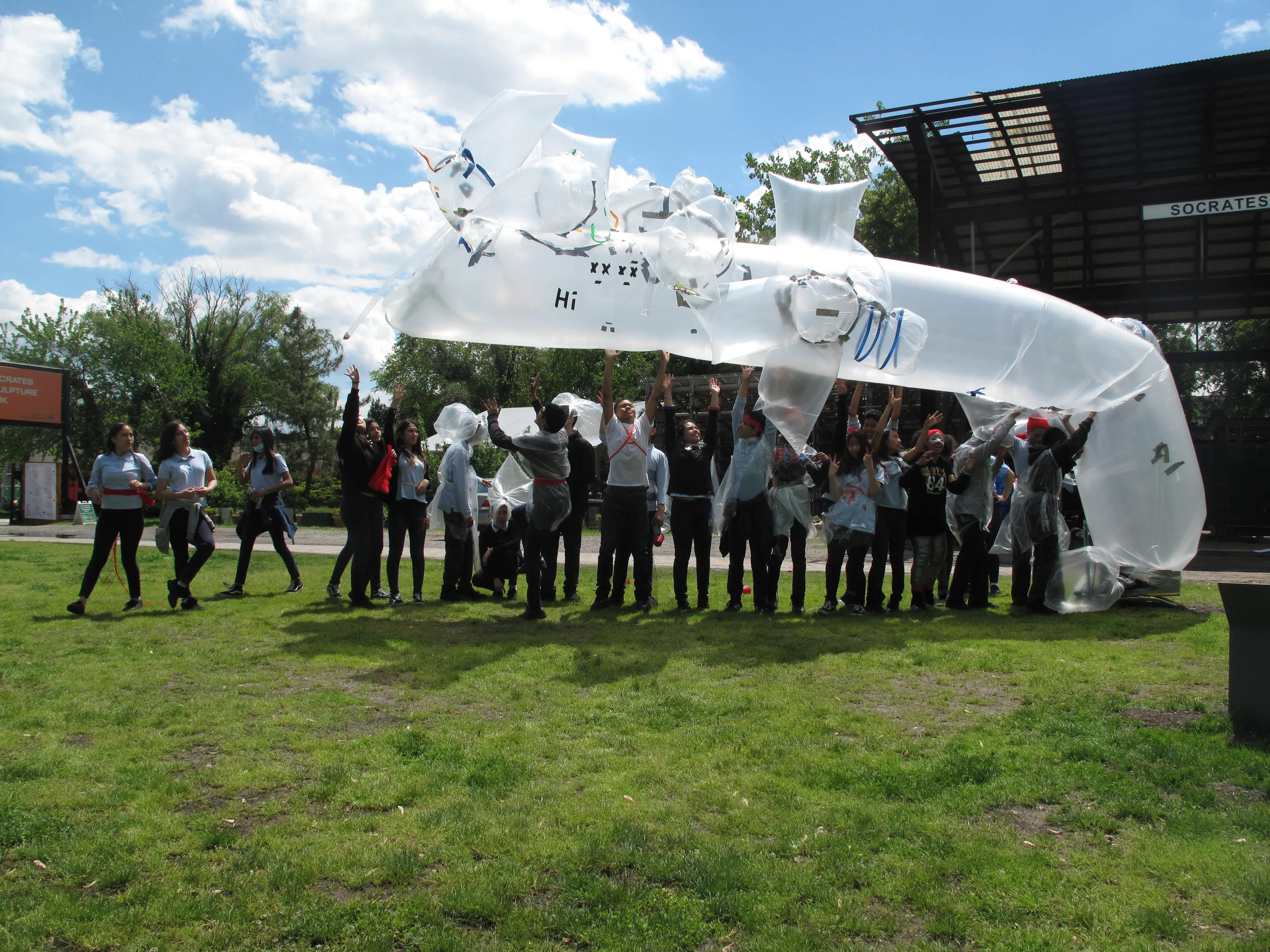 Photo of many kids playing with large transparent inflatable sculpture.