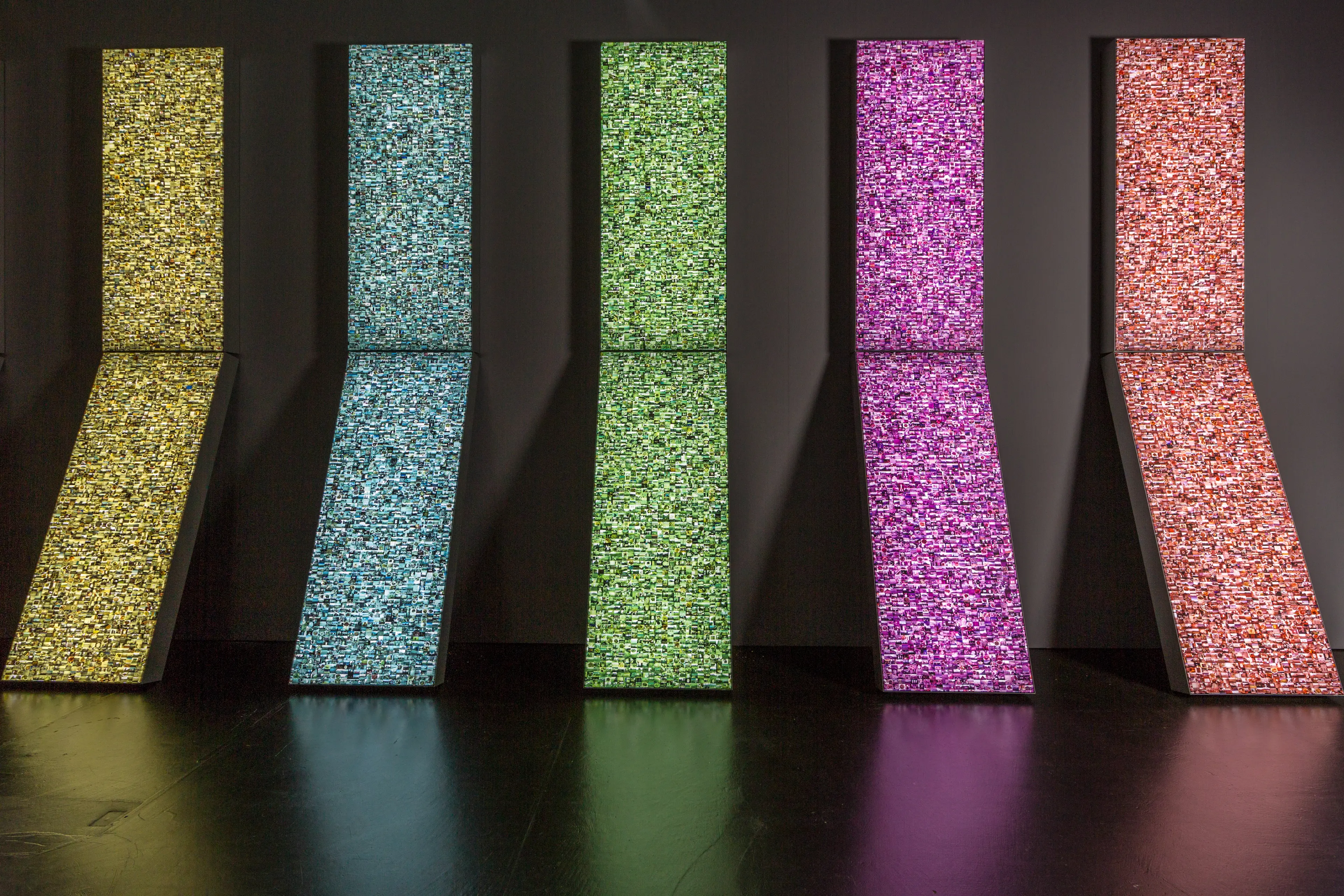 Picture of video installation with 5 V-shaped lcd screens leaning agains the wals, each of different color and composed of smaller images.