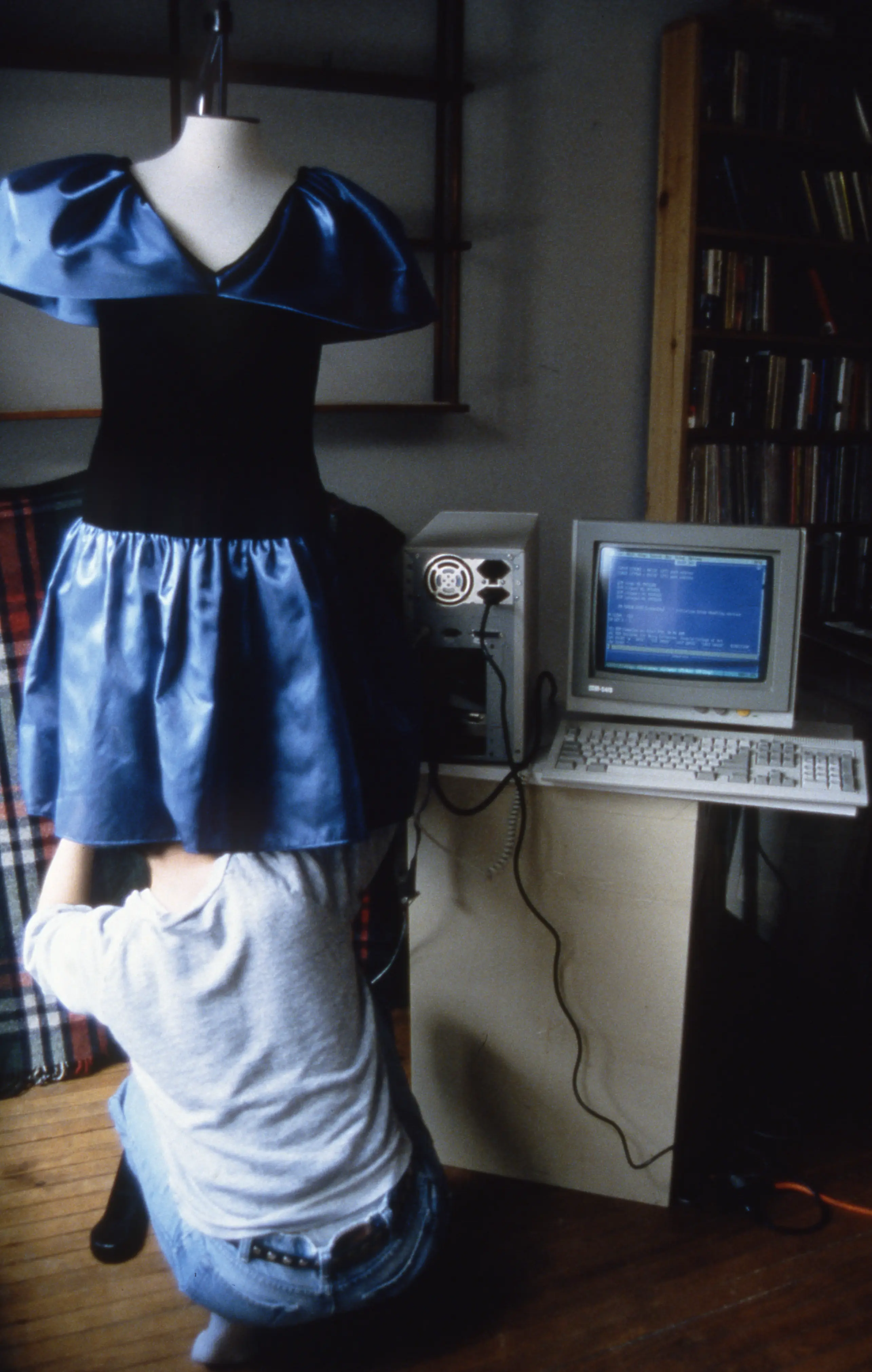 Photo of Nancy underneath the blue dress in her studio with old CRT monitor and keyboard in the background.